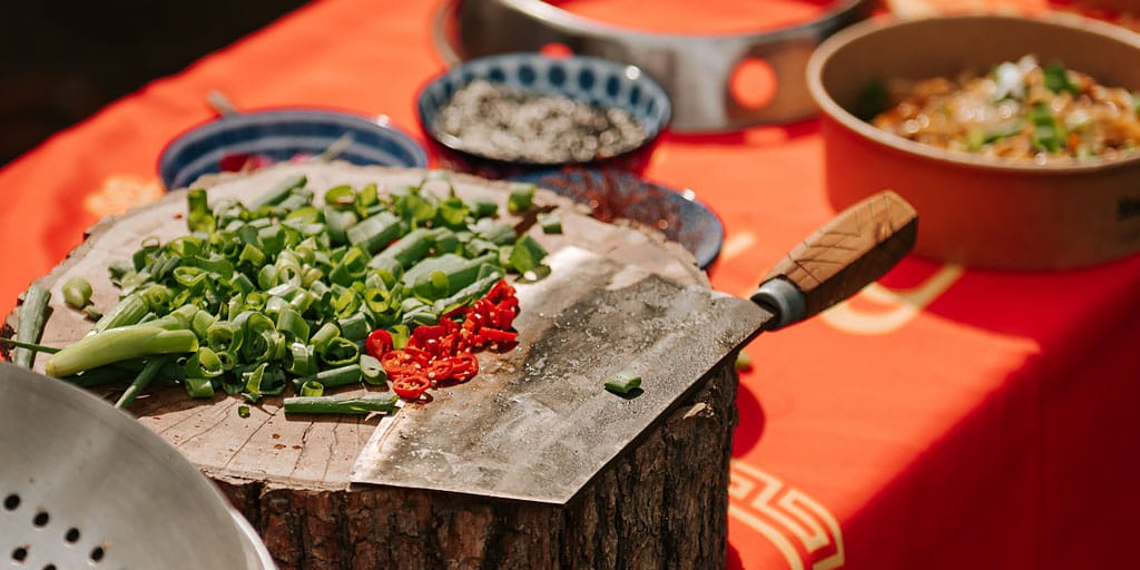 Chińska drewniana deska, tasak i posiekana dymka. - live cooking.